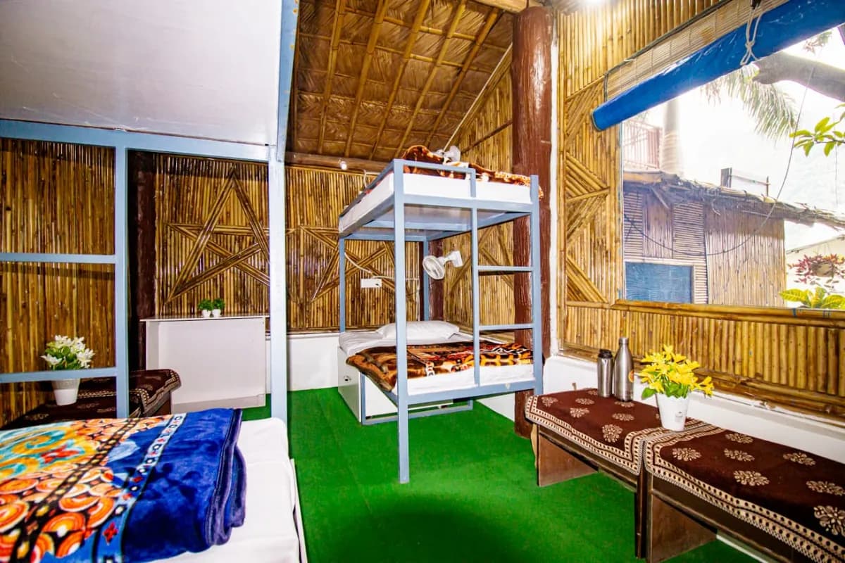Shared dormitory room with bunk and single beds in a bamboo cottage at our Rishikesh yoga school
