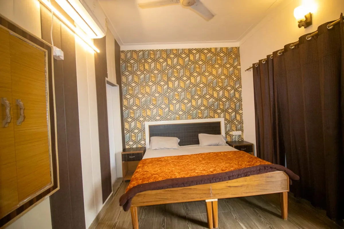 Private double room with feature wallpaper wall and wooden bed at our Rishikesh yoga campus