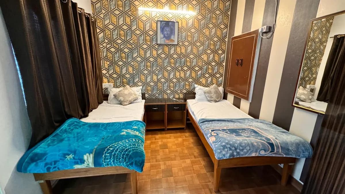 Twin-shared room with two single beds and decorative wall at Swaastik Yog School Rishikesh