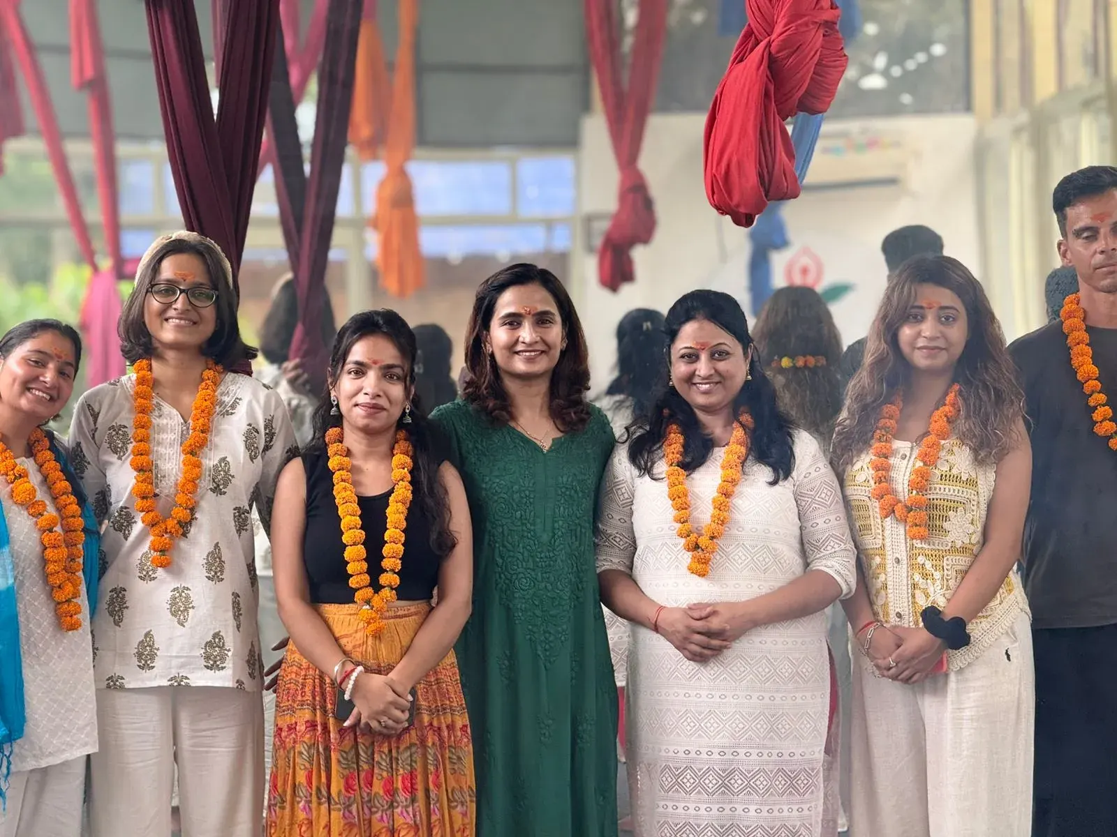 Graduates in marigold garlands celebrating together in the aerial yoga studio