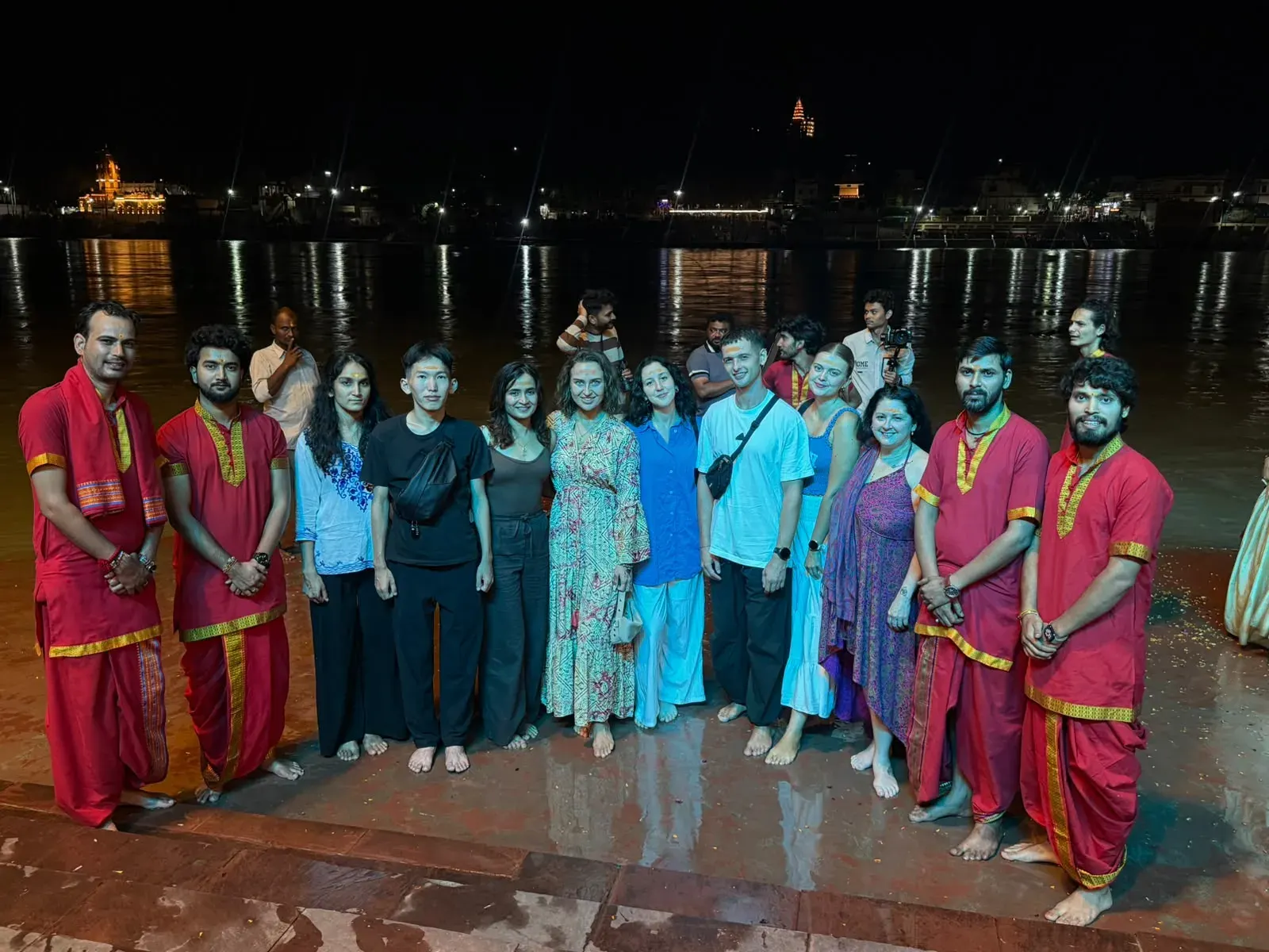Students with priests in red at the evening Ganga Aarti on the riverside ghat in Rishikesh
