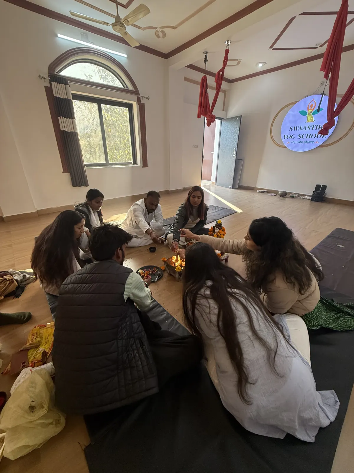 Students seated in a circle during a candlelit prayer and meditation ceremony at Swaastik Yog School