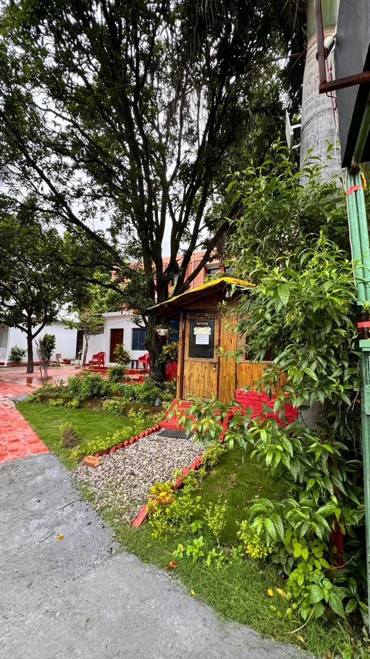 Lush garden path with pebble beds and bamboo office hut at the Swaastik Yog School campus in Tapovan, Rishikesh