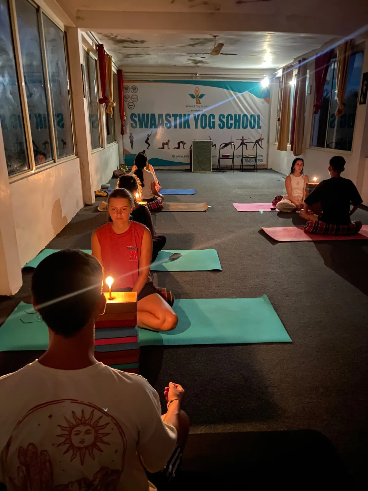 Students practising candle-gazing (Trataka) meditation in the evening yoga hall at Swaastik Yog School, Rishikesh