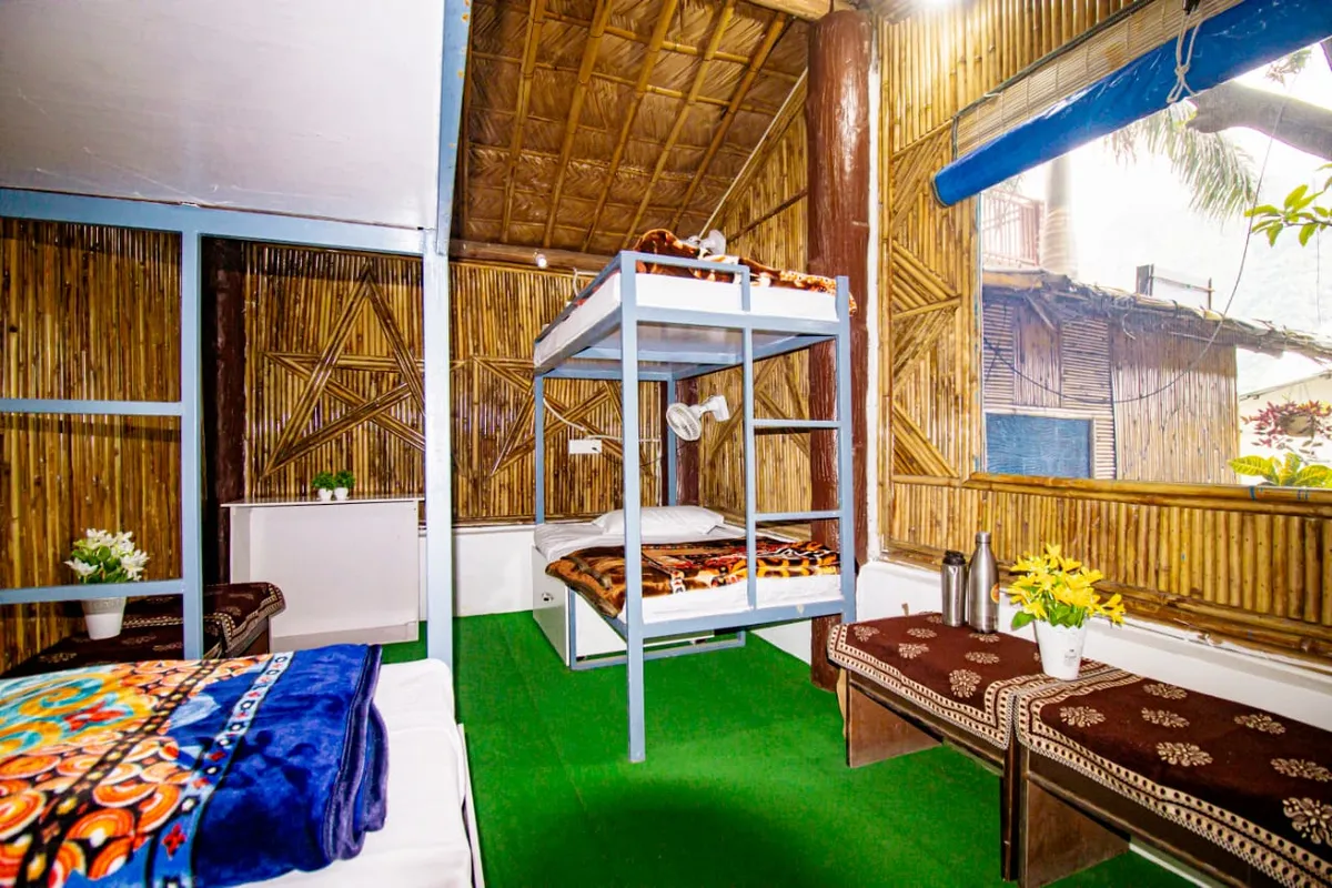 Dormitory room with bunk beds, fans and bamboo walls at Swaastik Yog School in Tapovan, Rishikesh