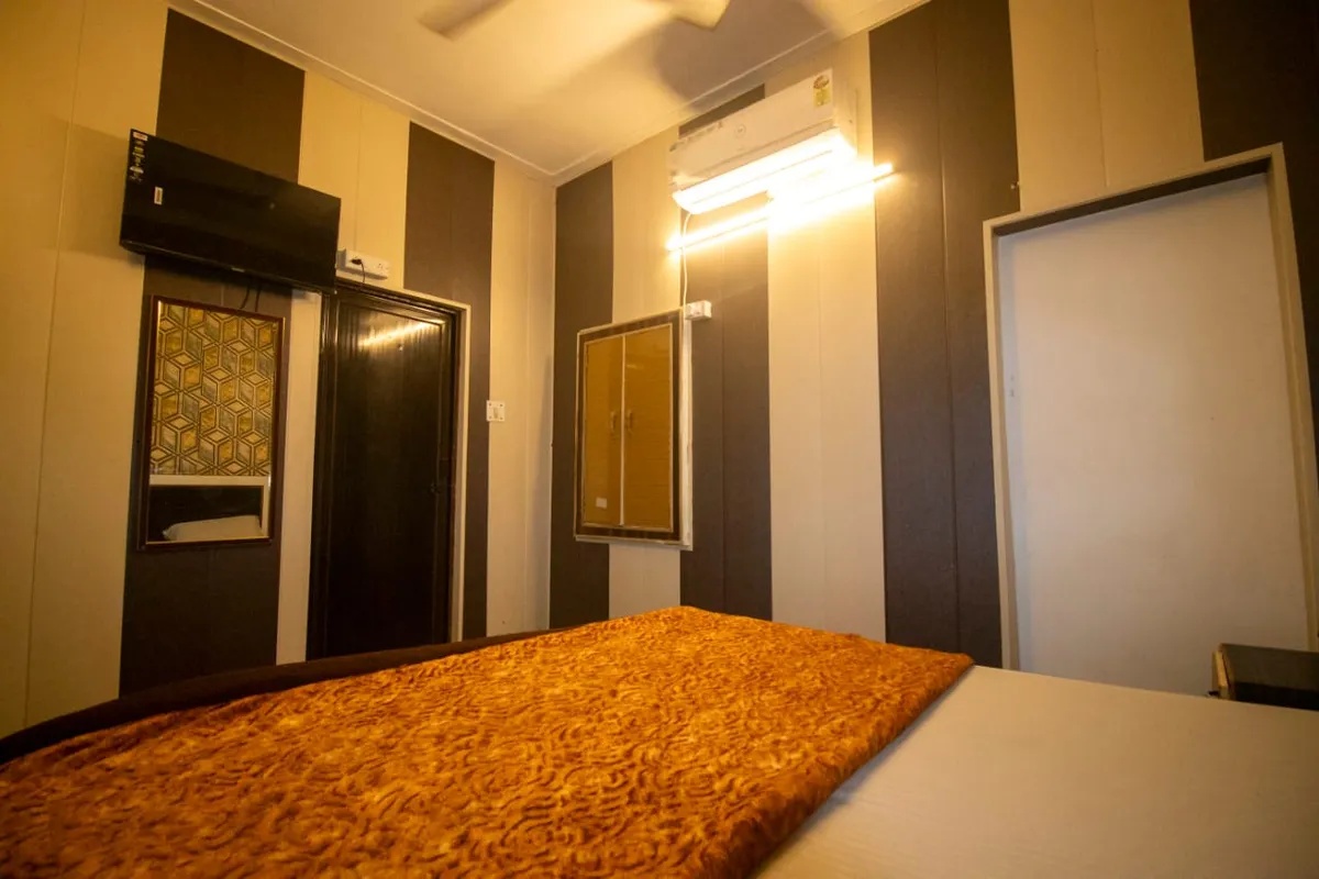Private room at Swaastik Yog School with a double bed, a split air conditioner, a wall TV, a mirror and a wardrobe